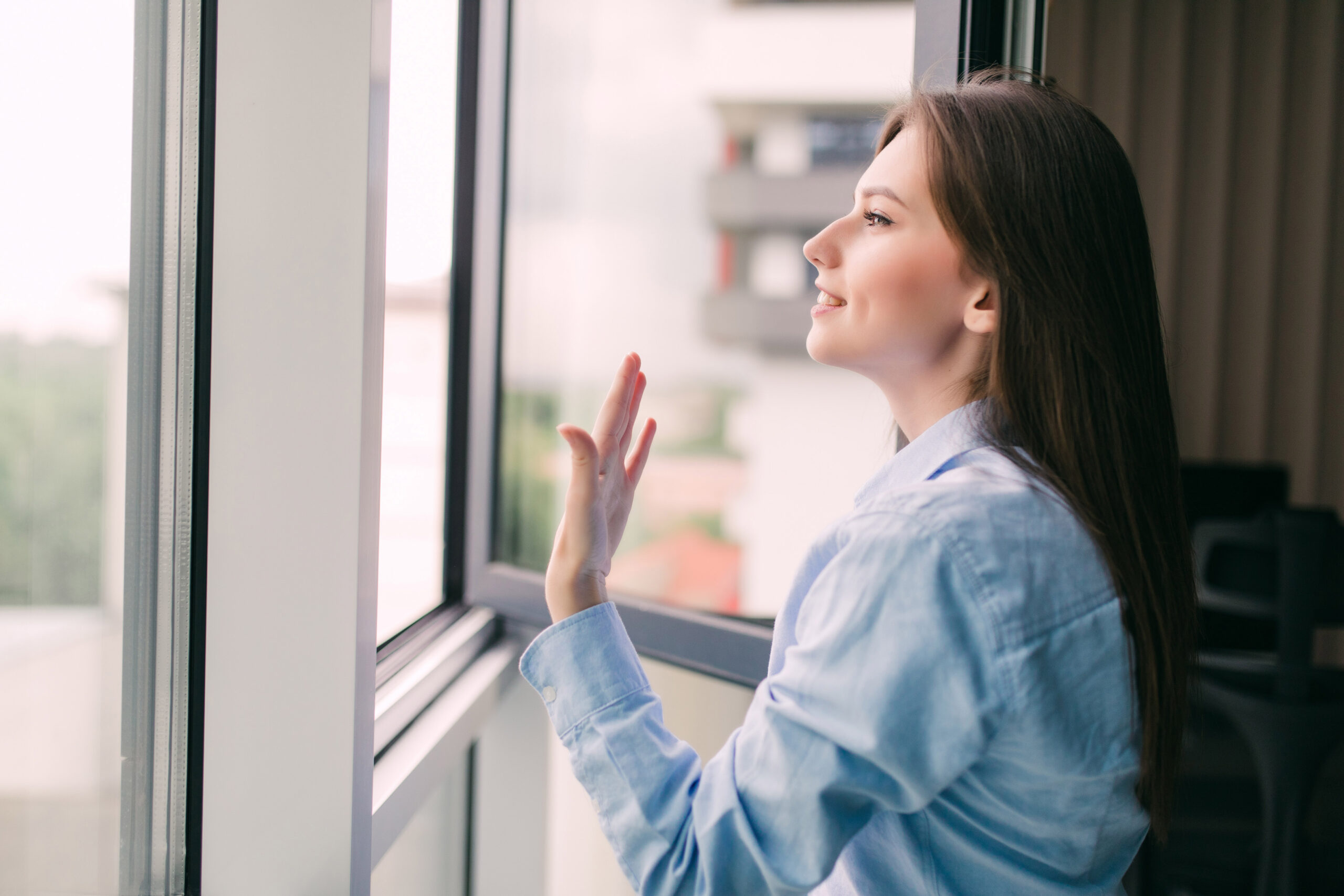 Foto für Blog Beitrag ELHADO Im Winter richtig heizen. Frau steht vor offenem Fenster